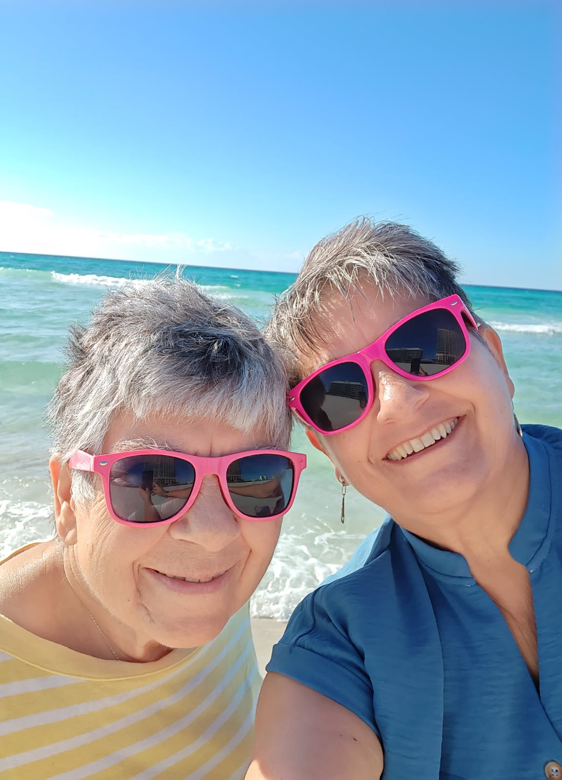 Sandy and her mom together at the beach, both smiling in the sun